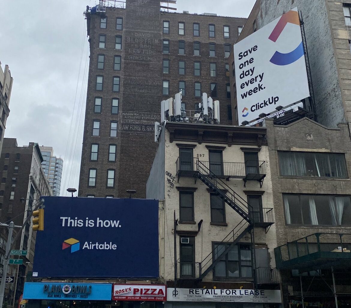 firebrand-brand-humor-blog-competition Image of 2 billboards in city, first by Clickup and the second by competitor Airtable.